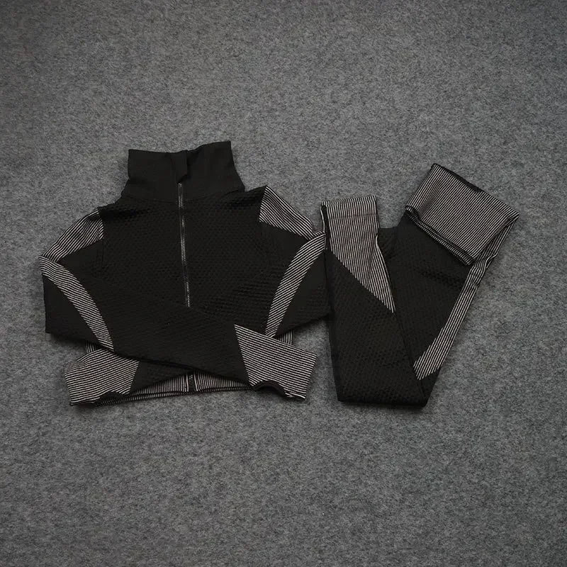 Black mesh sports crop top and matching leggings laid out on gray fabric, ideal for women's workouts and athleisure.